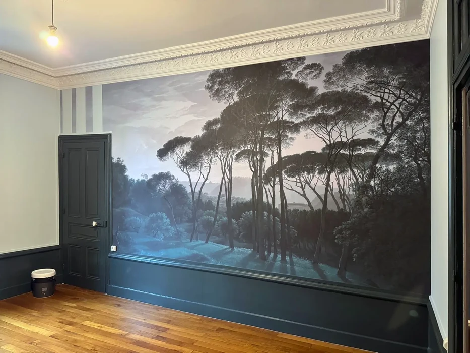 Intérieur résidentiel avec peinture murale panoramique représentant un paysage forestier au coucher de soleil