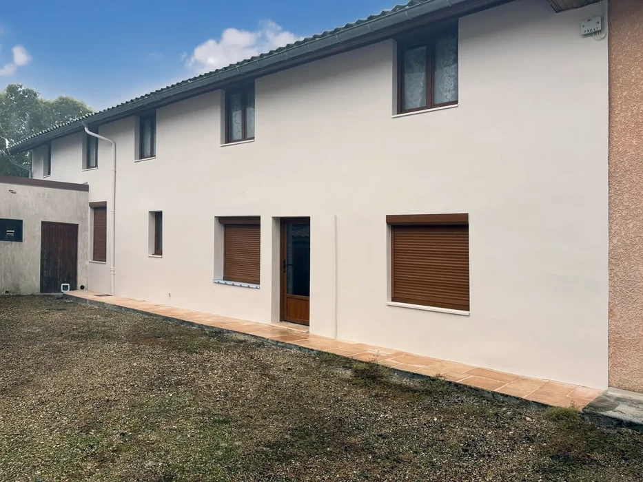 Façade extérieure de maison individuelle récemment rénovée avec crépi beige clair