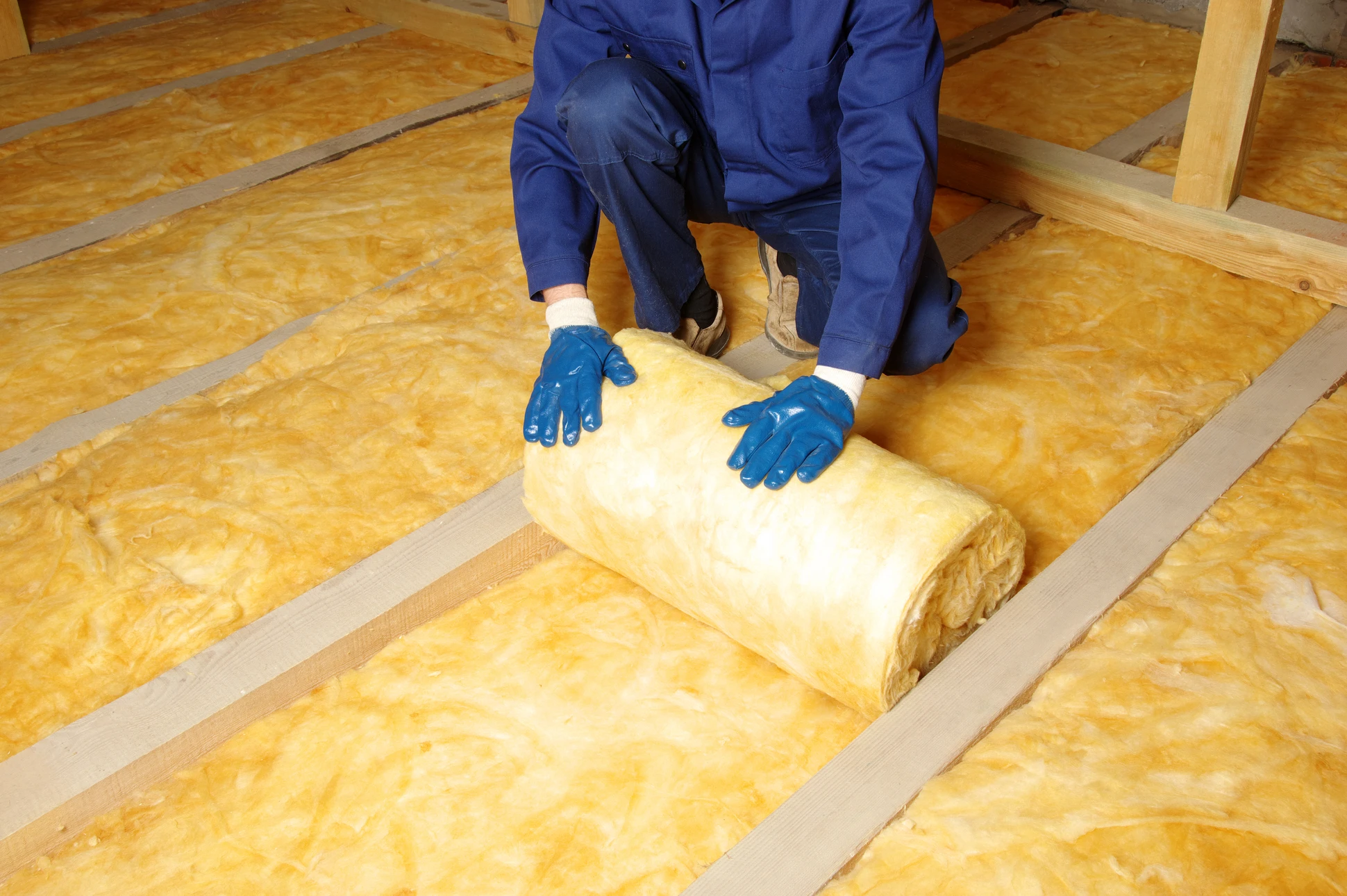 Ouvrier en b&acirc;timent installant de l'isolant thermique entre les montants d'une cloison int&eacute;rieure